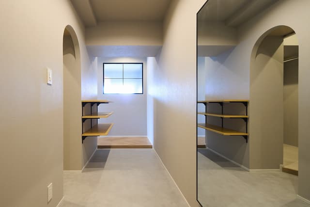 玄関は、モールテックス塗装で土間風の作りに。幅が広くゆったりとしているので、アウトドア用品やベビーカーなどを置いても余裕があります。正面には寝室の窓から光を取り入れるため、アイアンの室内窓を取りつけました。玄関左手にはR型の開口があり、ファミリークローゼット・洗面スペースにつながっています。