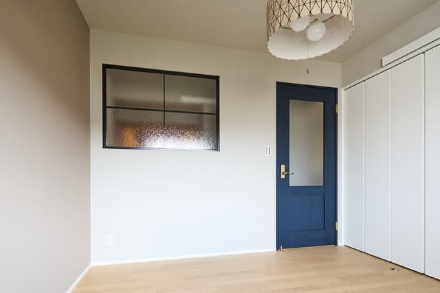 寝室です。アイアン窓とネイビーで、少し落ち着いた空間に。一面のみ、グレージュのアクセントクロスを取り入れています。入って左側にはクローゼットがあり、衣替えしたお洋服などを収納することができます。クローゼット脇には、書斎への入り口があります。