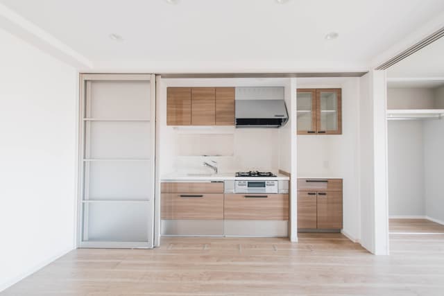 キッチン。サイズはミニマルで、右の棚を含め収納が充実しています。食洗機はついていません。来客があるときに水回りを隠せる引き戸がついています。