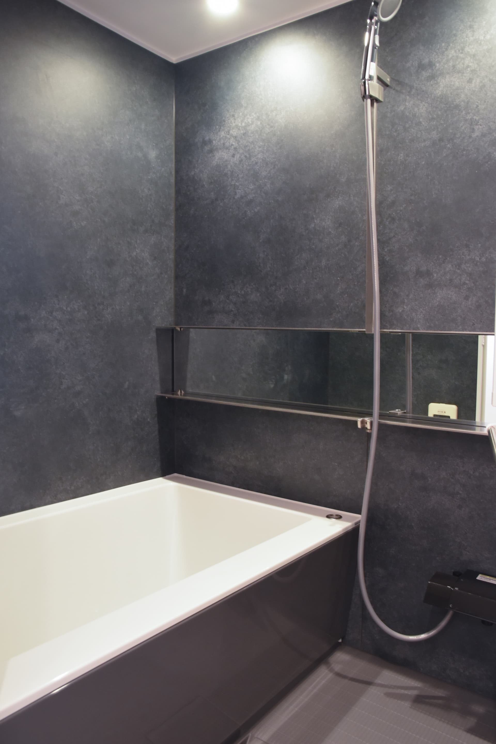 浴室: ブラックモルタル調にステンレスのフラットバーが映える