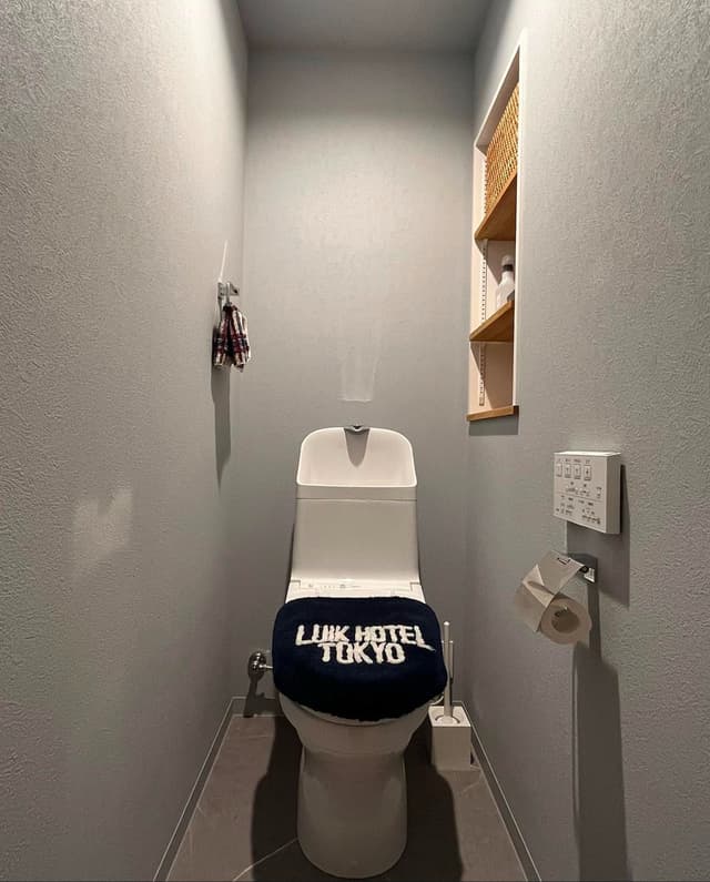 ブルーグレーの壁紙と撥水タイルで彩られたトイレ