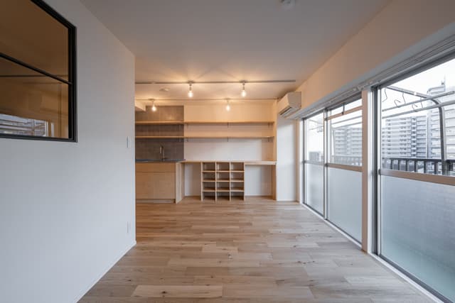 リビングの壁側から眺めた景色。造作カウンターには、棚をつけています。カウンター左側のエリアは、無印のゴミ箱が2つ収まるように設計し、中央の棚も無印の籠がぴったり収まるようにしました。
右側は、椅子を置き、化粧スペースや作業台として活用しています。