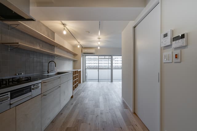 廊下からリビングへ入ってすぐのエリア。左手にキッチン、右手のドアを入ると寝室兼ワークスペースがあります。