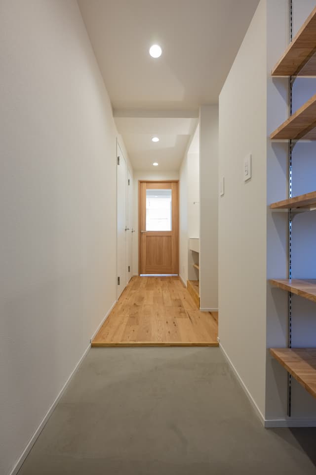 玄関入ってすぐ。土間部分を広くとっているので、大きな荷物を持ったり置いても、広々と使えます。正面のリビングへ繋がるドアはバルコニーからの光が抜けるように、設計しました。