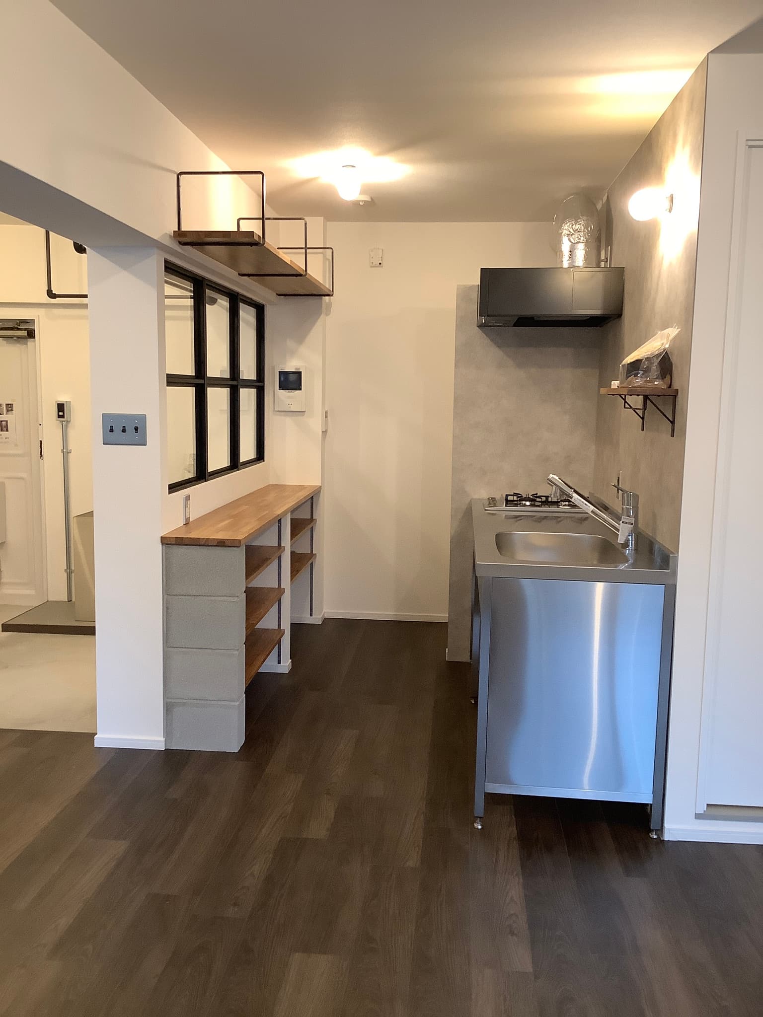 キッチンはステンレス製です。ガスコンロは２口です。キッチンの後ろにはオープンの収納棚があります。