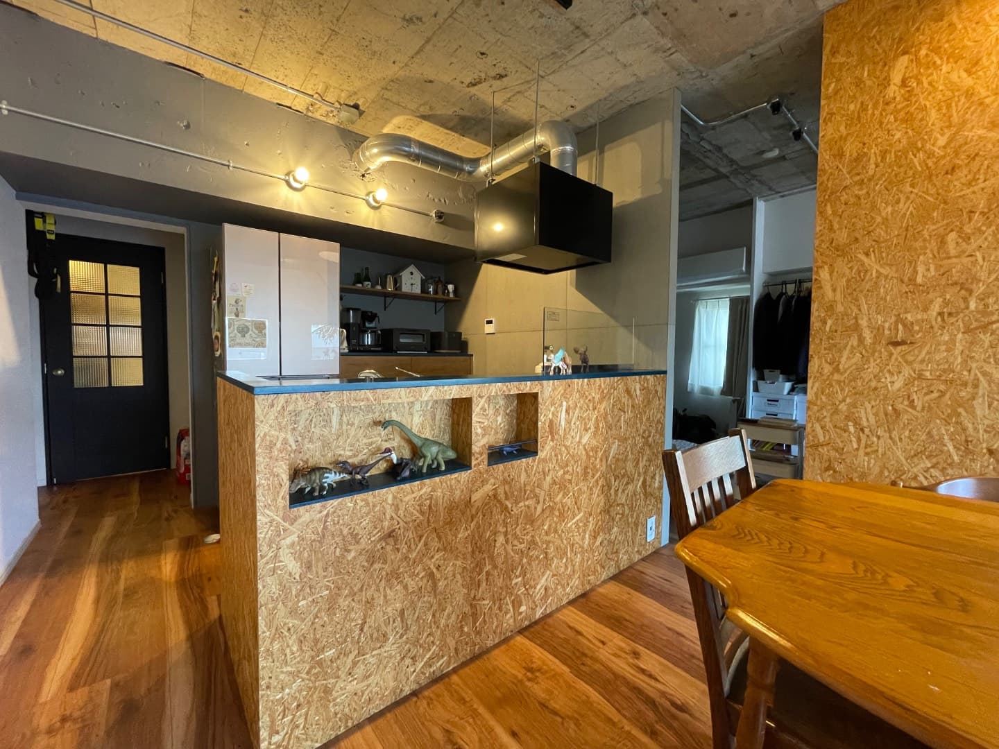 キッチンカウンターもOSBで造作し、空間全体に統一感と温かさを出しています。カウンタートップの濃いグリーンがアクセントです。
カウンターの一角にはさりげなくコンセントを設け、ケーブル類をすっきりと収納できる工夫も。
天井にはダクトをあえて見せることで、インダストリアルな雰囲気を出しました。