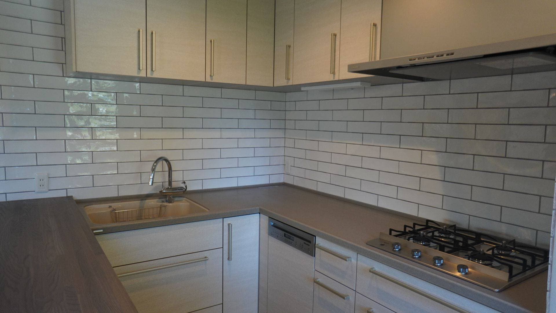 こだわりのキッチン。大きめの白タイル。キッチンはトクラスのコラージア、Milleの食洗機を内蔵。