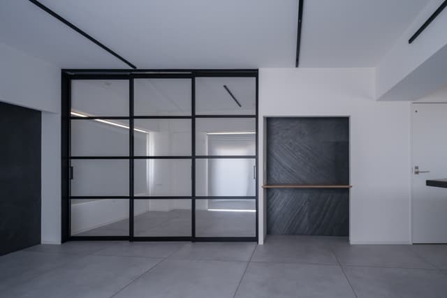 寝室との区切りは部屋が広く見えるように透明な引き戸で緩やかに区切っています。
寝室側の天井部には扉に沿ってカーテンレールを設置しているので必要に応じてカーテンで遮光や目隠しをすることも可能です。