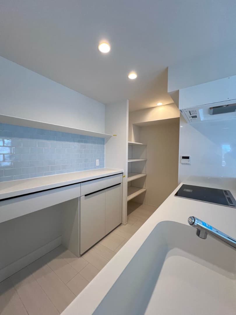 キッチンボードの上は水色のタイル張り。小物を飾れる飾り棚やゴミ箱置きコーナー、パントリーもあります。