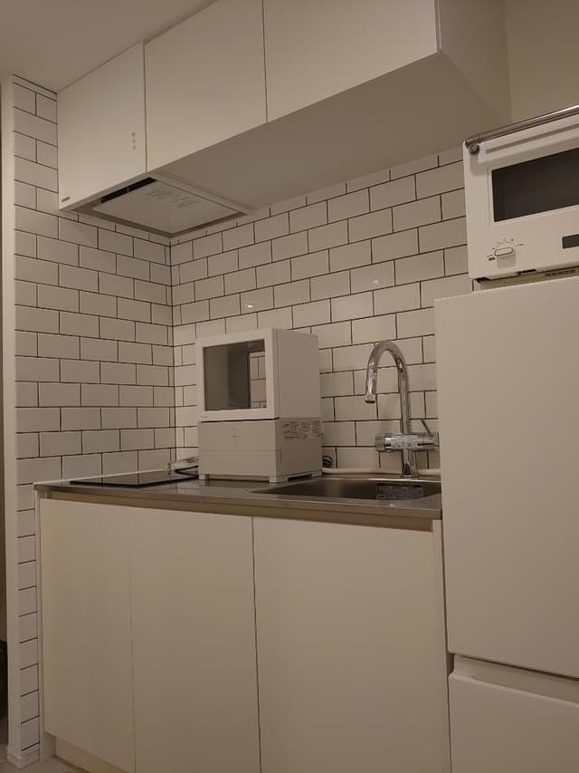 ホワイトで統一をした唯一無二なミニマムコンパクトなキッチンエリアです。
平田タイルの白いサブウェイタイルに目地は上品なセラドンカラー＊キッチンの天板はステンレスのバイブレーション仕上げ＊三化工業のモダンなIH＊水栓は浄水器機能付きハイグレード仕様のグローエ社のミンタ。もし売却をするときには未使用のPanasonic食洗機もお付けさせていただきます。※冷蔵庫と電子レンジは付きません。