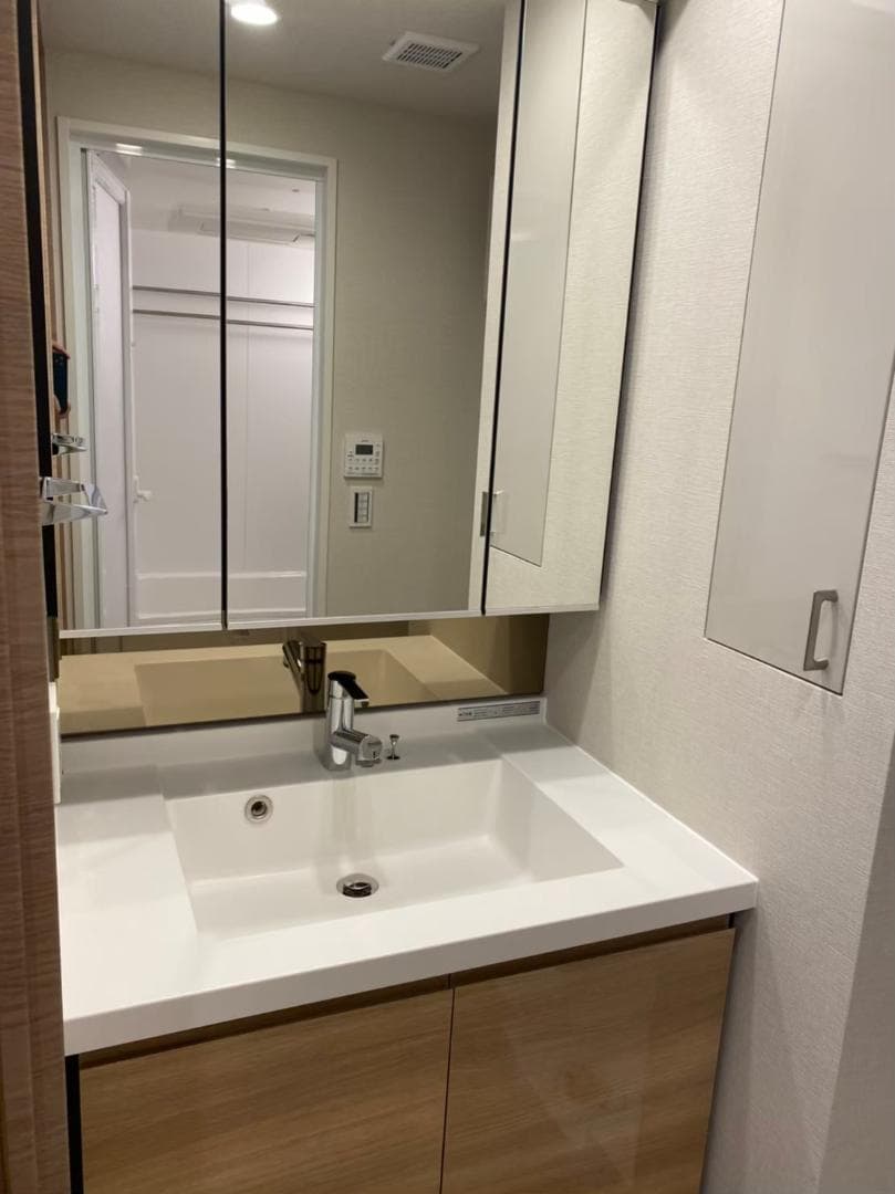 三面鏡仕様の洗面台で身支度がしやすく、鏡裏収納により小物もすっきり整理できます。シャワー水栓付きで清掃や使い勝手も良好。さらに洗面台横の収納スペースにより、タオルや日用品もまとめて保管でき、清潔感のある空間を保てる点が気に入っています。（入居前写真）