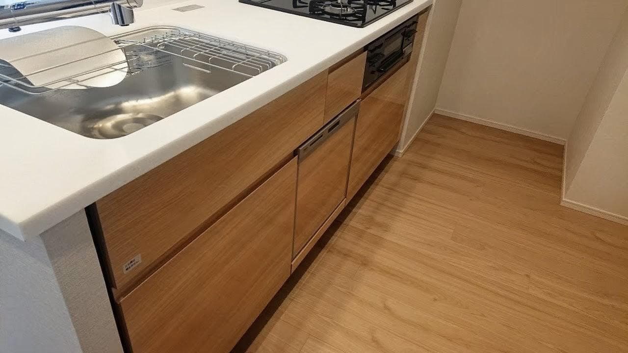 カウンターキッチンは3口コンロ（グリル付き）で、日々の料理がしやすい点が気に入っています。食洗機付きで家事の負担も軽減できます。さらに、リビング収納と同様に天井から足元まで高さのある奥行き十分の収納を備えており、食材や調理器具もすっきり整理でき、キッチンまわりを清潔に保てます。（入居前写真）