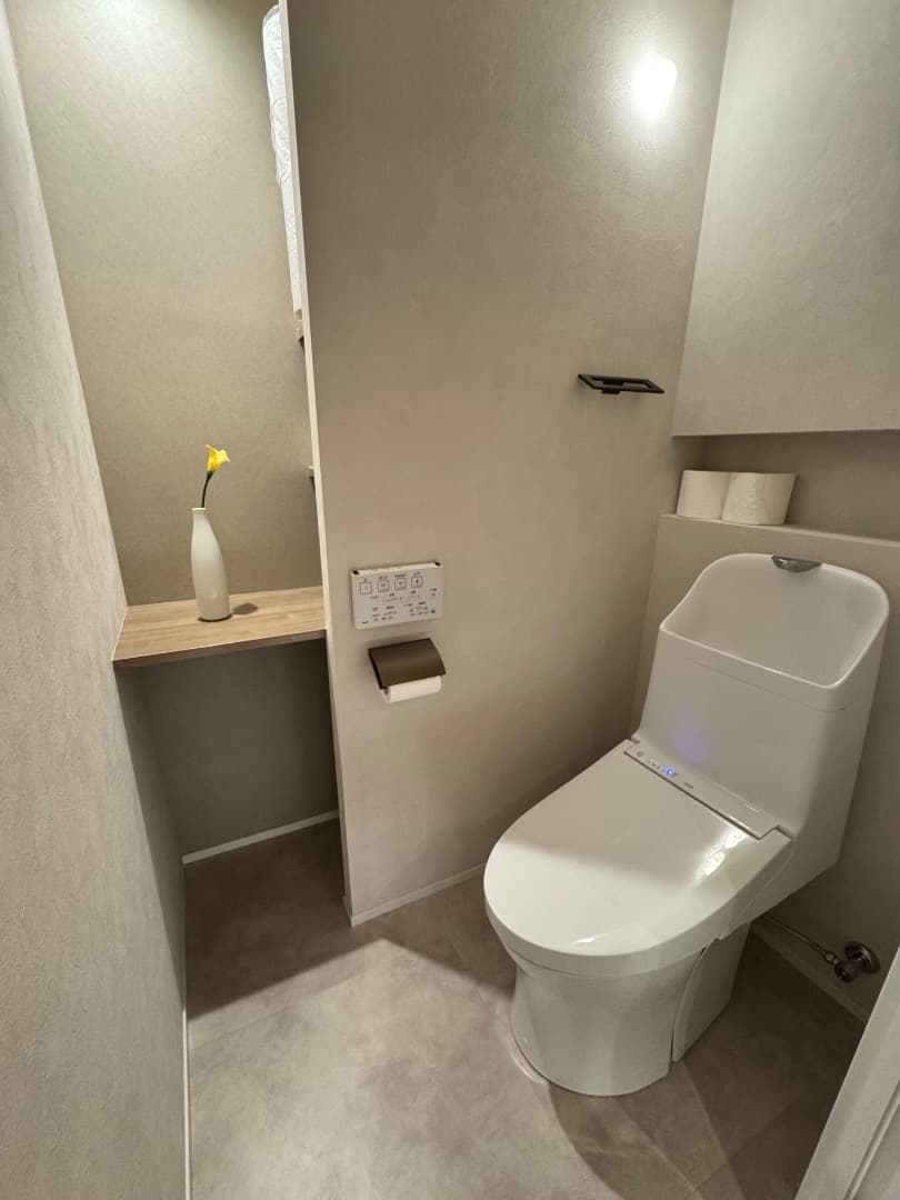 廊下からトイレを見る。便器背面にはトイレットペーパーを開けるニッチを造作。入って正面には飾り棚を設置。棚の奥は収納も可
能。