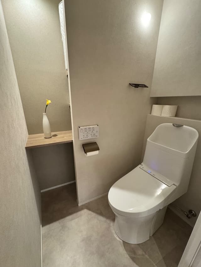 廊下からトイレを見る。便器背面にはトイレットペーパーを開けるニッチを造作。入って正面には飾り棚を設置。棚の奥は収納も可
能。