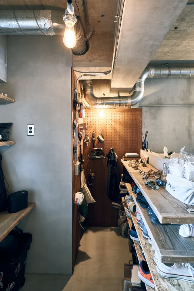 玄関から入って左の土間です。正面はパンチングボードになっています。左右に古い足場板とOSB板の棚があります。